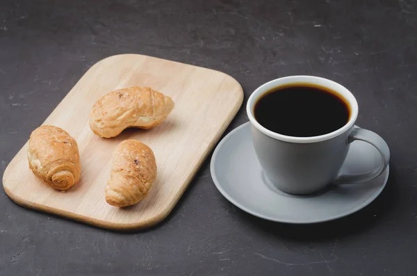 Taza gris con café negro y bandeja de madera con croissants en da — Foto de Stock