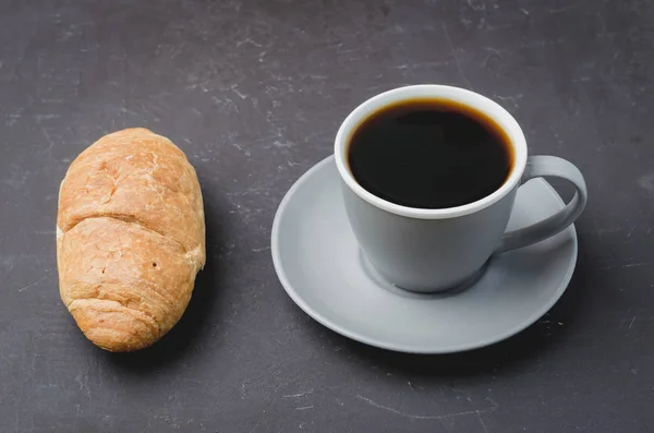 Διάλειμμα για καφέ. Γκρι κύπελλο με μαύρο καφέ και κρουασάν σε σκούρο b — Φωτογραφία Αρχείου