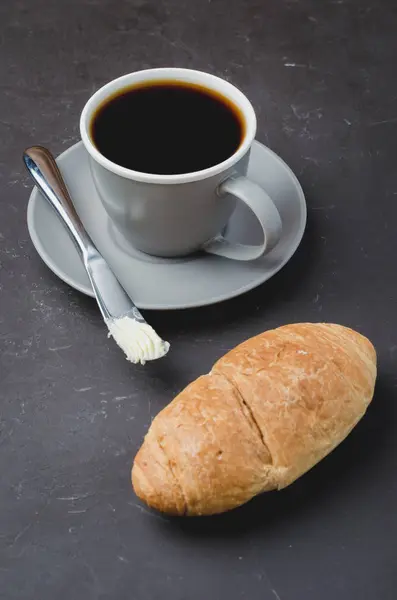 Pausa para café com croissant, faca de manteiga e xícara de café preto — Fotografia de Stock