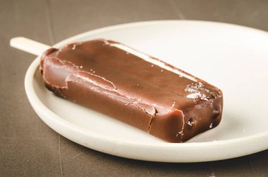 Dondurma. Beyaz çubuk üzerinde ev yapımı koyu çikolatalı dondurma.
