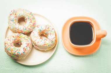 Kahve molası. Kahveli turuncu fincan ve bir tabak donat. Üst görünüm