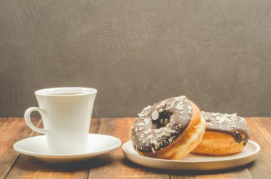 Kahve molası. Sütsüz kahve ve çikolata jöleli bir donat. Ahşap arkaplan.