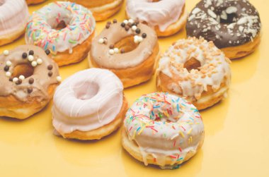 Colorful donut pattern on yellow background. Sweet food concept.