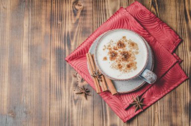 Eggnog. Geleneksel noel kokteyli beyaz bardakta tarçın çubukları ve kırmızı peçetede anason. Üst Manzara. Ahşap arkaplan.