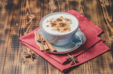 Eggnog. Geleneksel Noel kokteyli mavi bardakta, tarçın çubukları ve kırmızı peçete ve ahşap masa üzerinde anason. Gecenin arka planı ıslak pencere