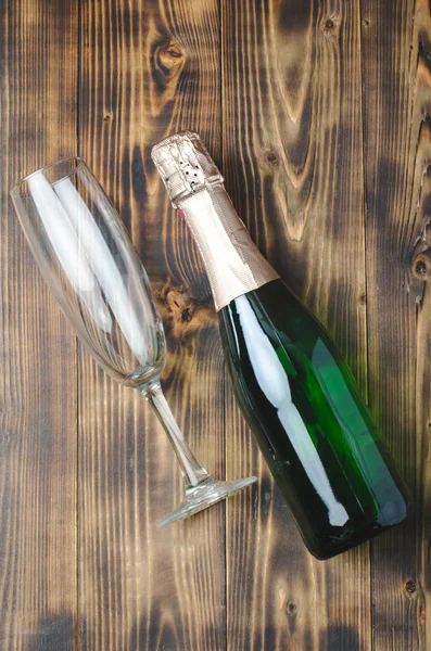Fles mousserende wijn en een glas op een houten achtergrond. Bovenkant — Stockfoto