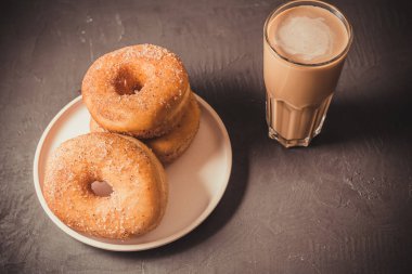 Tabakta çörekler ve koyu bir masada bir bardak kahve. Üst 