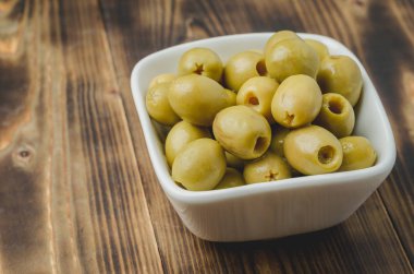 Ahşap arka planda bir kasede yeşil zeytin turşusu. Kopyalama alanı