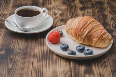 Bir fincan kahveyle nefis kahvaltı ve taze kruvasan. 