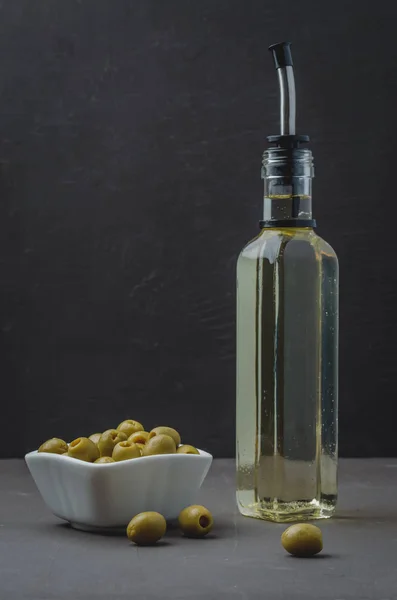 Zielone oliwki w białej ceramicznej misce i szklanej butelce oliwki o — Zdjęcie stockowe