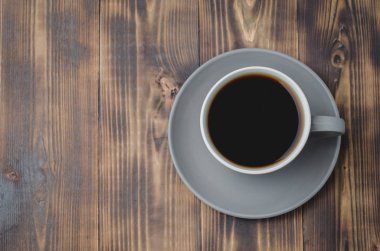 Koyu ahşap masanın üzerinde koyu kahve olan gri fincan. Üst görünüm ve