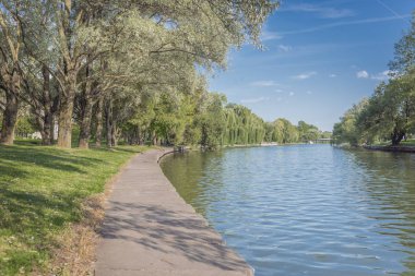 Şehir parkındaki nehir. Toprak seti boyunca ağaçlar. Güzellik doğası