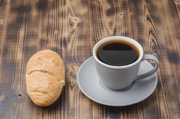 Kávészünet. Szürke csésze fekete kávé és croissant on dark w — Stock Fotó