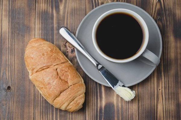 Pause café avec couteau à beurre croissant et tasse de café noir — Photo