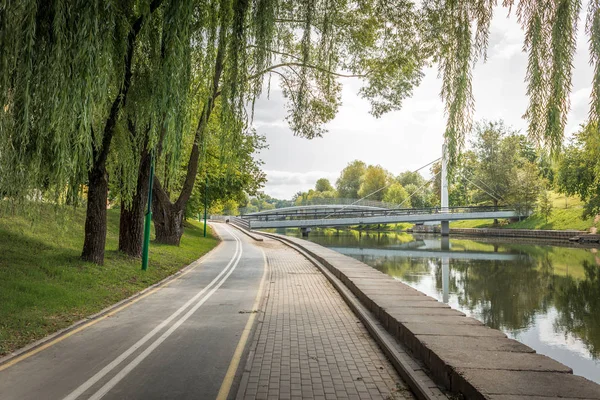 Pista ciclabile nel parco con alberi verdi lungo il fiume. Bellezza — Foto Stock