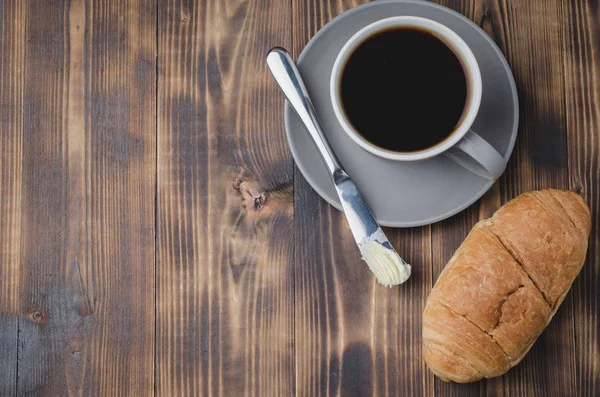 Pausa para café con cuchillo de mantequilla de croissant y taza de café negro — Foto de Stock