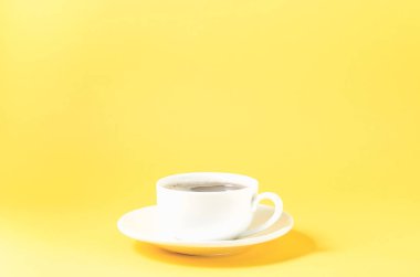 Sarı zemin üzerinde fincan tabağı olan beyaz bardak. Sarı zemin üzerinde beyaz bardak.