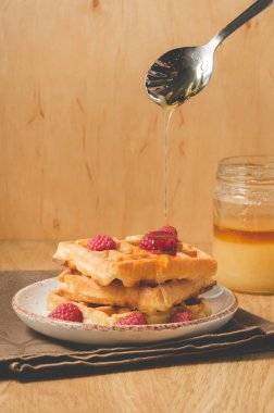 Böğürtlenli waffle, bir kaşıktan bal, bir kaşıktan bal dökülen böğürtlenli waffle.