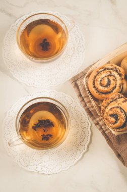 Tahta bir sepetin içinde haşhaş ile iki bardak çay ve haşhaş, beyaz bir sepetin içinde ahşap bir sepetin içinde, en üstteki manzarada.