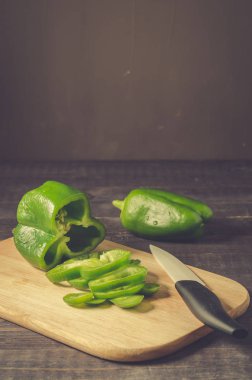 Tahtada taze kırmızı biber, tahta üzerinde kırmızı biber. Fotokopi alanı olan koyu bir zeminde tahta bir tahta kesiği.