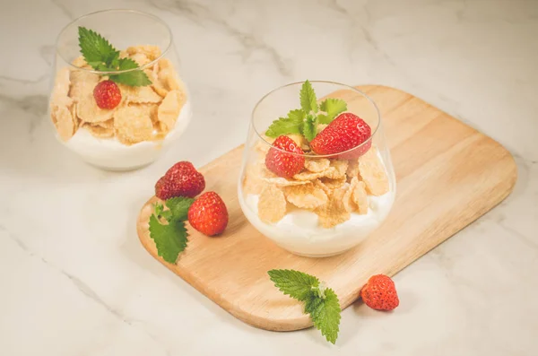 含玉米片 草莓和薄荷糖的自制酸奶 白桌面上有装饰过的玉米片薄荷糖和草莓 — 图库照片