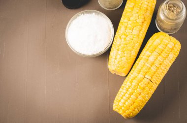 Mısır. Karanlık bir masada tuzlu ve baharatlı haşlanmış mısır. Üst görünüm ve kopyalama alanı