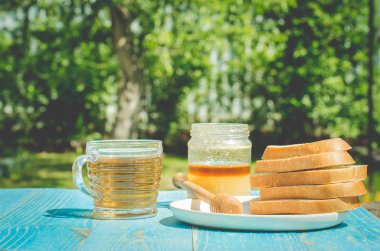 Ballı çay ve ahşap masa arkasında kesilmiş beyaz hamur işleri. Yazın susuz kalınca ballı çay