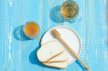 Ballı çay ve ahşap masa arkasında kesilmiş beyaz hamur işleri. Üst görünüm