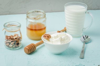 Sağlıklı kahvaltı geçmişi. Bal, süt, süzme peynir ve mavi masada ceviz..