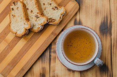 Çay fincanı ve masada dilimlenmiş hamur işleriyle kahvaltı. Üst görünüm