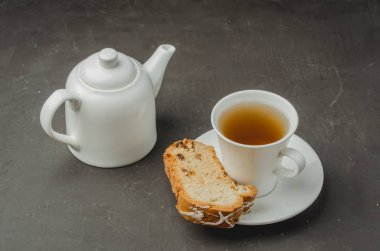 Beyaz çay fincanı ve üzerinde hamur işleri olan çaydanlık. Seçici odak