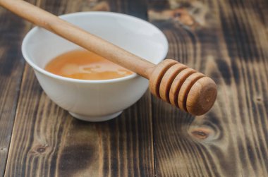 Beyaz bir kasede ballı, ahşap bir masa. Seçici odak