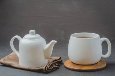 - Çay. Bir fincan çay ve çaydanlık. Siyah taş bir masada beyaz eşya. Seçici odak