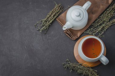 Kekik çayı beyaz bir fincanda ve çaydanlık siyah bir taş masada. Kopyalama alanı ve üst görünüm