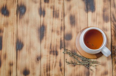 Tahta bir masada beyaz bir fincanda kekik çayı. Yukarıdan görüntüle, metin için boşluk