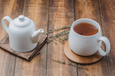 Kekik çayı beyaz bir fincanda ve çaydanlık da tahta bir masada.. 