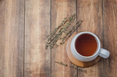 Tahta bir masada beyaz bir fincanda kekik çayı. Yukarıdan görüntüle, metin için boşluk