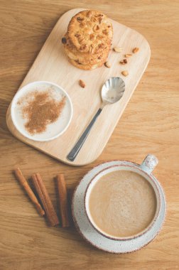 tarçınlı puding, kurabiyeler ve tarçınlı kahve / puding, kurabiyeler ve ahşap arka planda bir fincan kahve. Üst görünüm