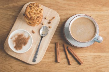 Tarçınlı puding, fındıklı kurabiye ve tarçınlı kahve / puding istiflenmiş cips kurabiyeleri ve ahşap arka planda bir fincan kahve. Üst görünüm
