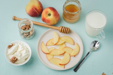 Sağlıklı kahvaltı geçmişi. Şeftali, bal, süt, süzme peynir ve mavi arka planda ceviz. Üst görünüm.