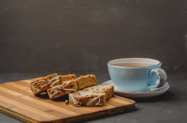 Çay fincanı ve hamur işleriyle kahvaltı. Koyu taştan bir masada tahta tahtada dilimlenmiş. Seçici odak