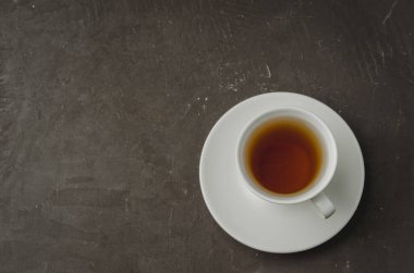 Koyu taş zemin üzerinde beyaz çay fincanı, üst görünüm ve telif alanı