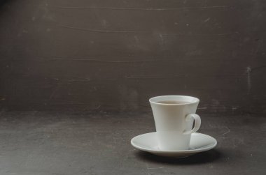Koyu taş zemin üzerinde beyaz çay fincanı, seçici odak ve telif alanı