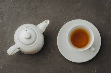 Çay fincanı ve çaydanlık koyu taş masada. Üst görünüm