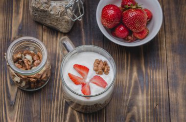 Tahta bir masada yoğurt, fındık ve çilek. Üst görünüm