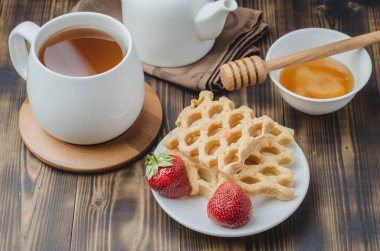 Çay, bal ve taze çilekle süslenmiş gofretlerle nefis bir kahvaltı. Üst görünüm