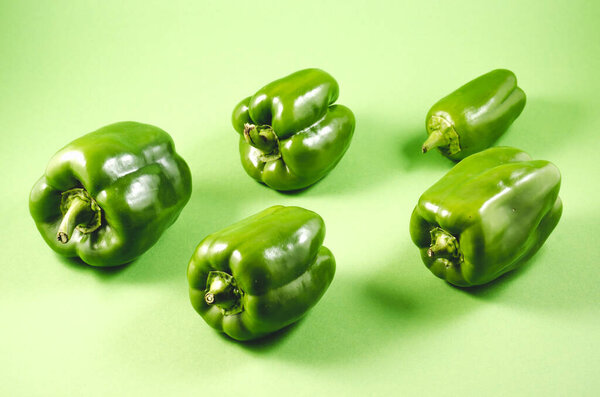 Green paprika pepper isolated on a green background / Heap of Fresh Green paprika pepper on green
