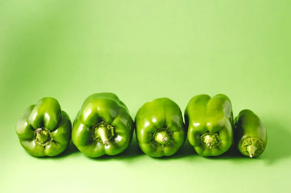 在绿色背景上分离的一排绿色红辣椒 绿色背景上的一排新鲜绿色红辣椒 — 图库照片