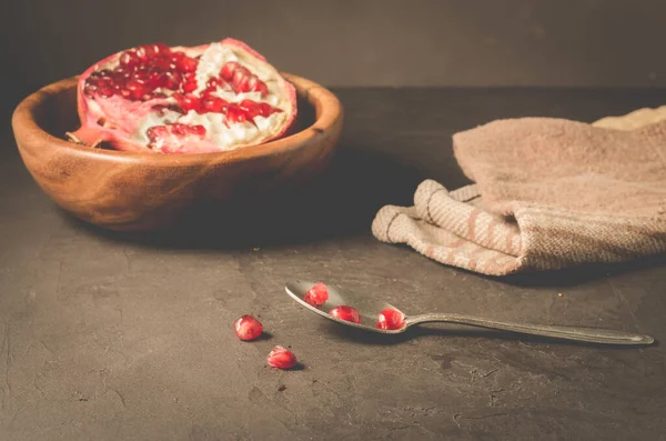 pomegranate fruit in a wooden bowl/pomegranate fruit in a wooden bowl and seeds on the table and in a spoon, selective focus