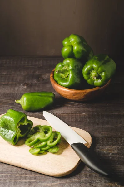 fresh paprika in a wooden bowl and cut on a board/fresh paprika in a wooden bowl and cut on a board on a dark table